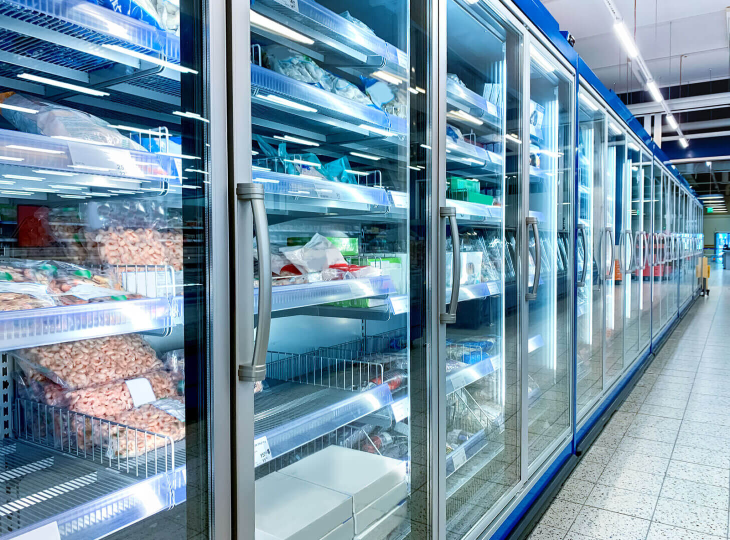 Góndolas refrigeradas de un supermercado con productos congelados y espacios vacíos, un punto que las góndolas conectadas ayudan a monitorear.