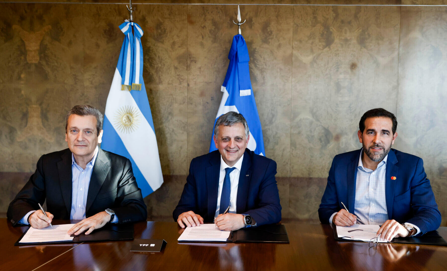 Directivos de YPF y Mastercard firman el acuerdo por la Tarjeta prepaga YPF - Mastercard en una sala institucional.