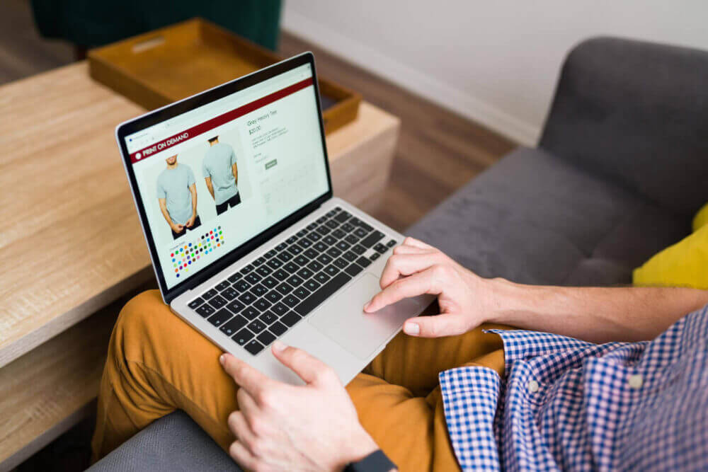 Persona consulta productos de indumentaria en una notebook, en una experiencia de comercio unificado entre el e-commerce y la tienda física.