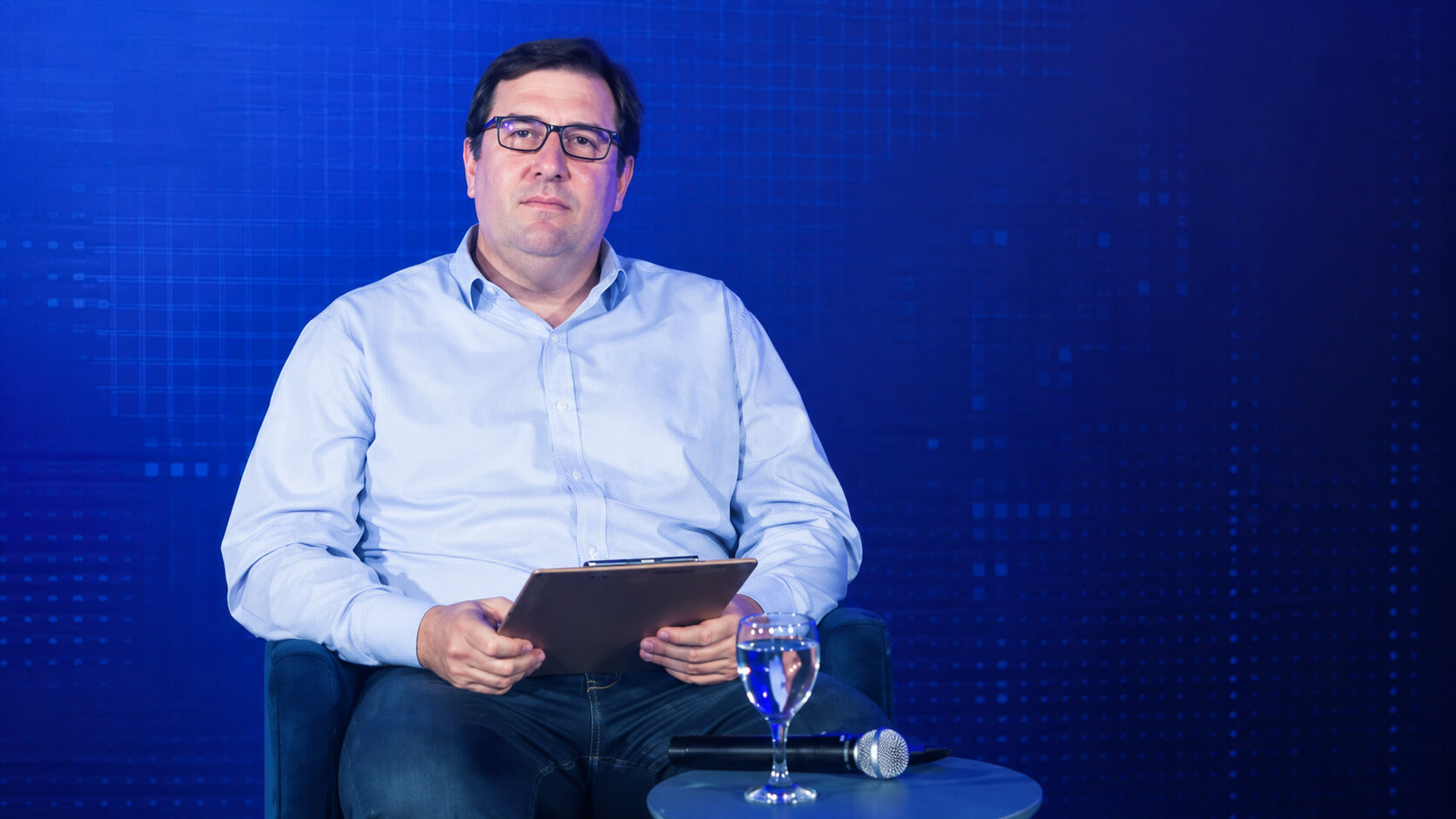 Mauricio Caggioli, CIO de ArcelorMittal Acindar, sentado en un escenario con una tableta, un micrófono y un fondo tecnológico azul.