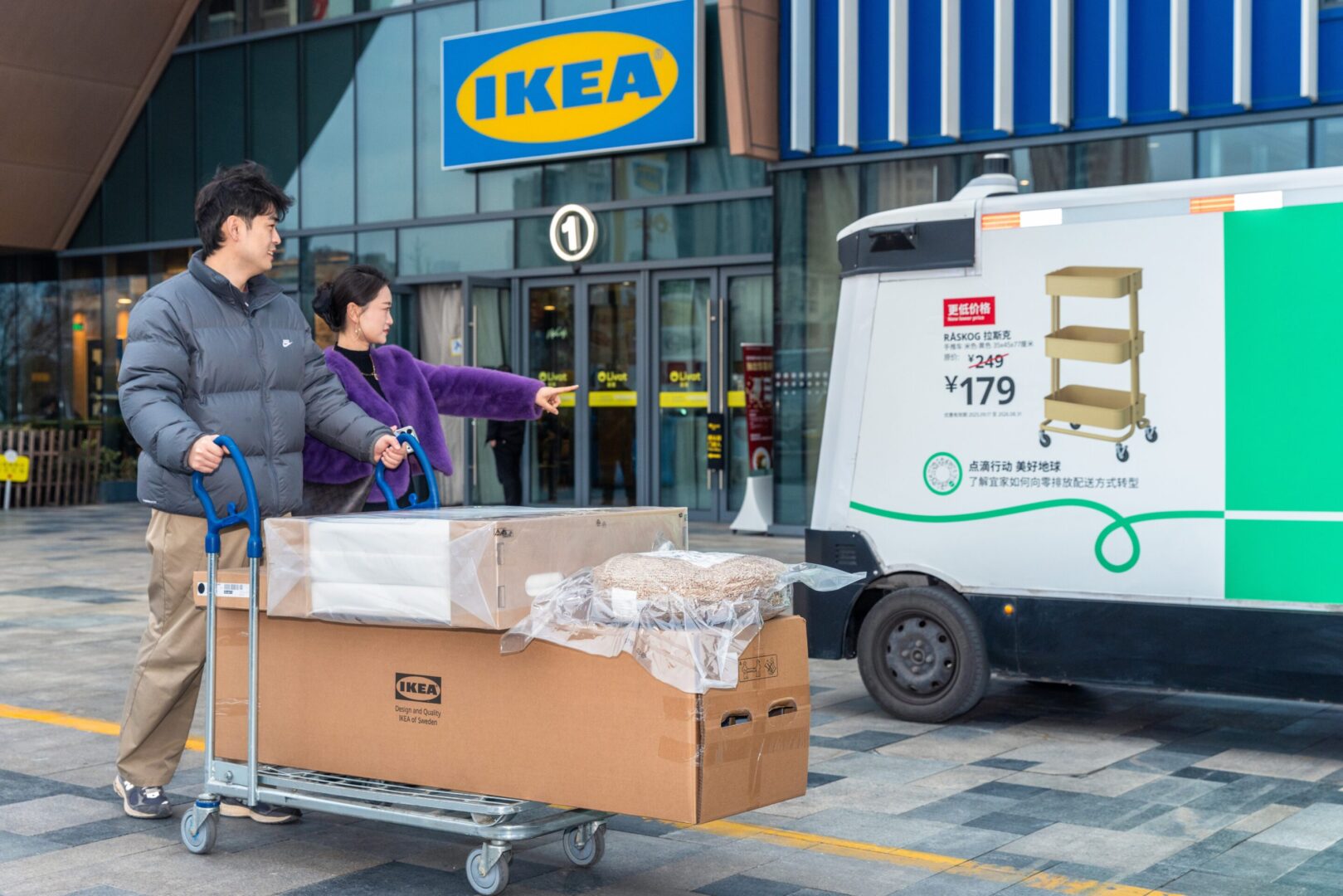 Vehículo autónomo de IKEA frente a una tienda en China mientras dos personas trasladan productos en un carro.