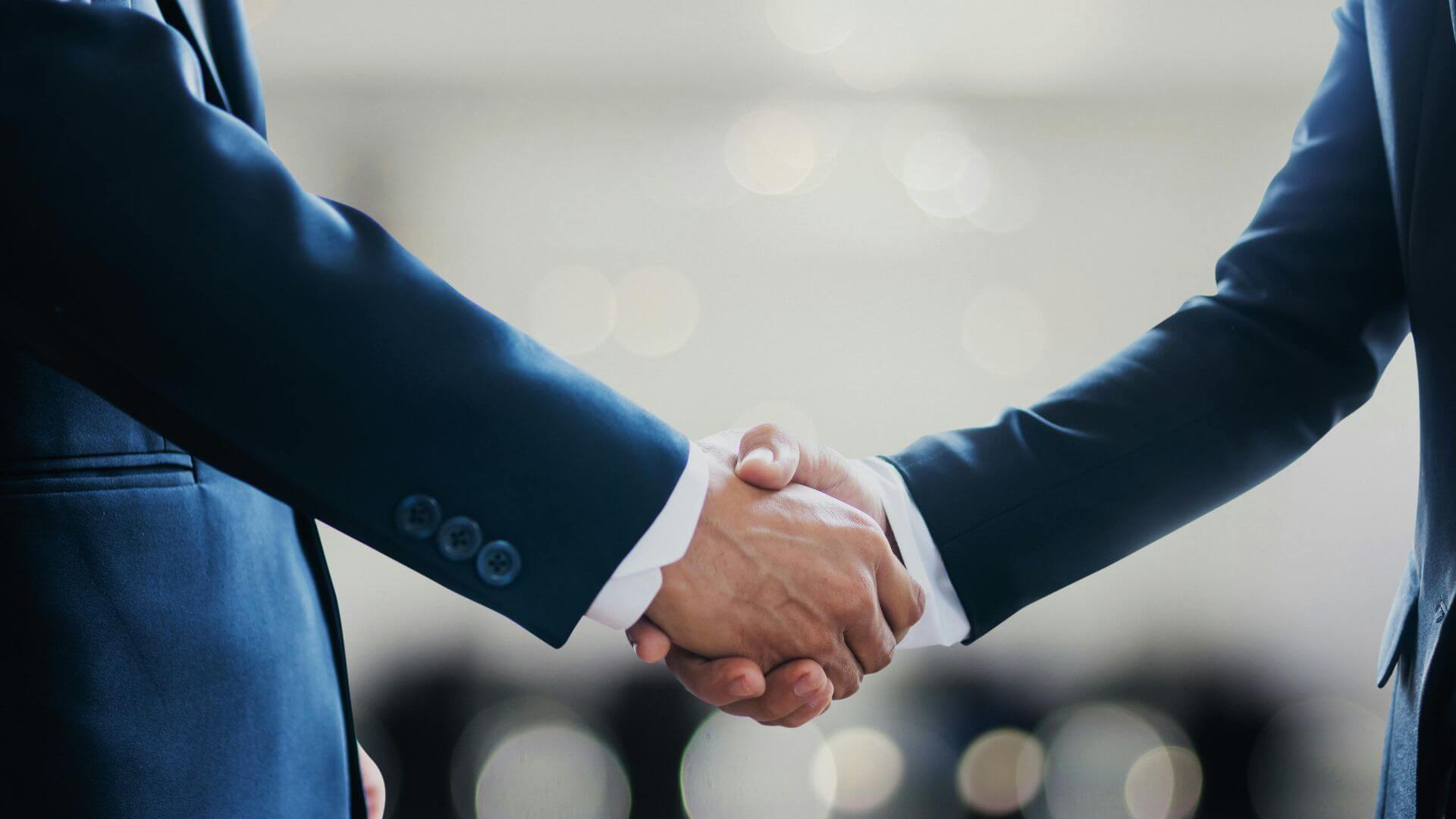 Apretón de manos entre dos ejecutivos que representa las operaciones e inversiones vinculadas con Electrify.