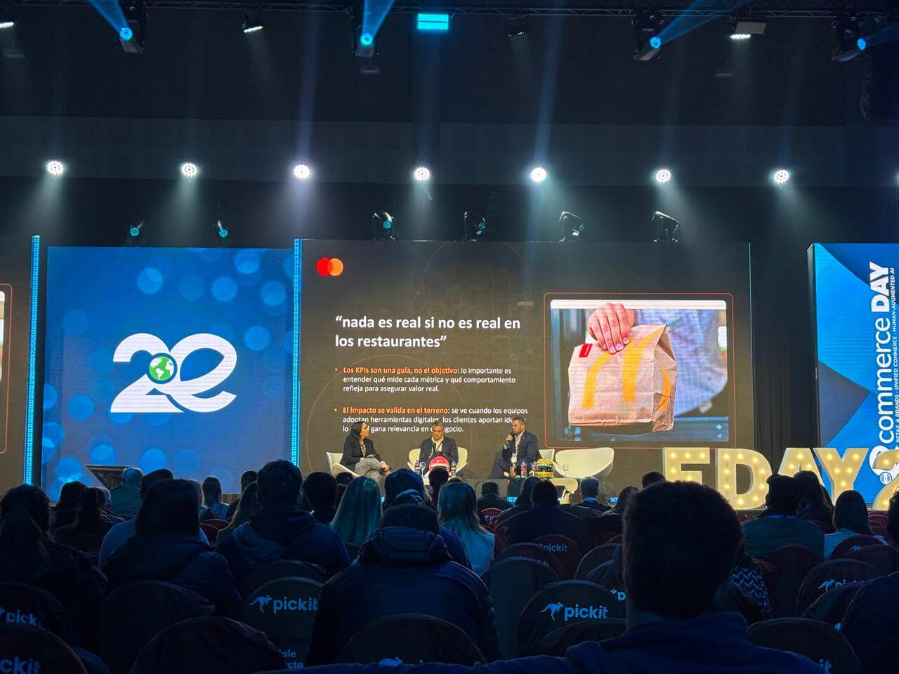Panel del eCommerce Day Argentina 2026 sobre personalización en e-commerce, con tres expositores en el escenario y una presentación sobre el impacto de las métricas digitales en los restaurantes.