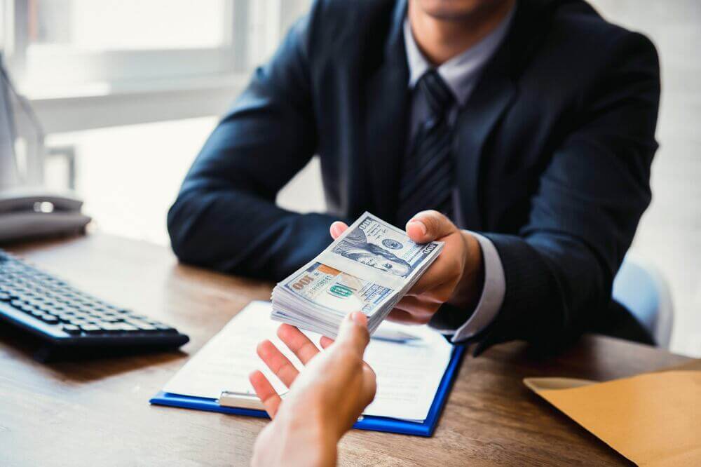 Ejecutivo entrega dinero a un cliente durante una operación de crédito, vinculada con el scoring crediticio.