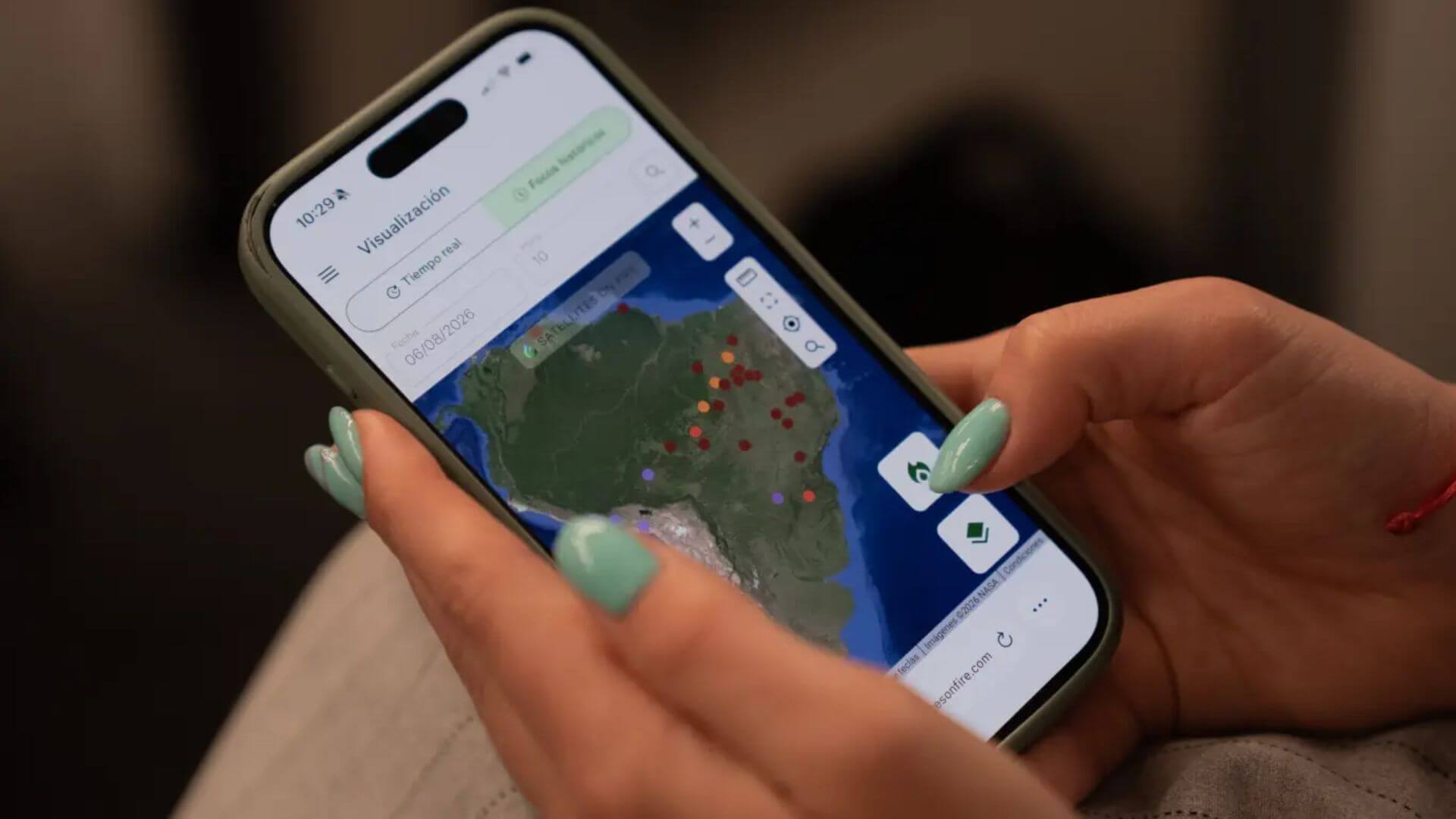 Celular con la plataforma de Satellites on Fire y un mapa con focos de incendio detectados en América del Sur.