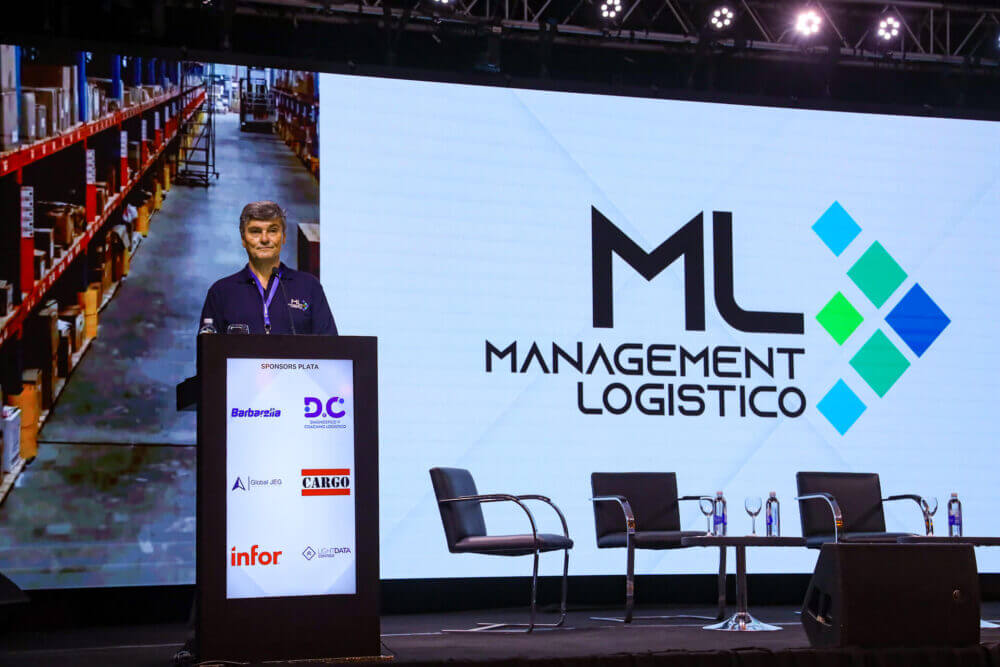 Expositor en el escenario de Management Logístico junto a una pantalla con la identidad del evento, que celebrará su edición 2026 en septiembre.