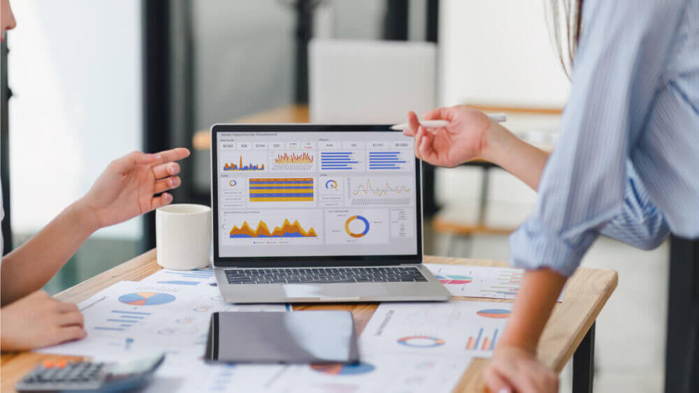 Dos profesionales analizan métricas y gráficos en una computadora para tomar decisiones sobre una estrategia de publicidad digital.
