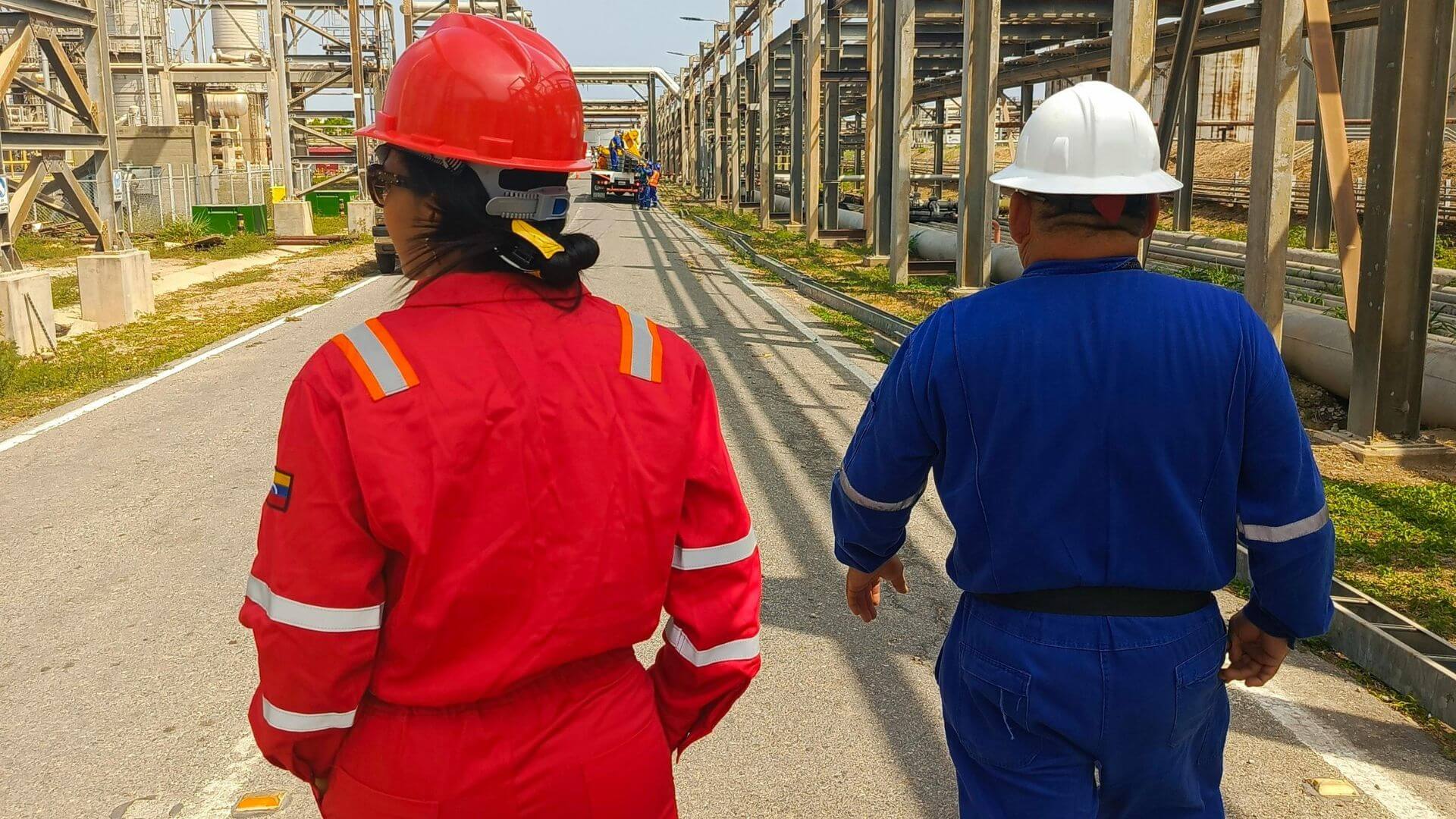 Dos operarios con casco y ropa de protección recorren una instalación como parte de las tareas de seguridad industrial.